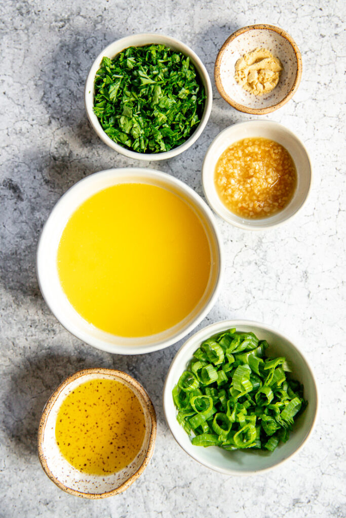 small bowls with olive oil, diced green onion, melted butter, minced garlic, chopped parsley, and dried mustard