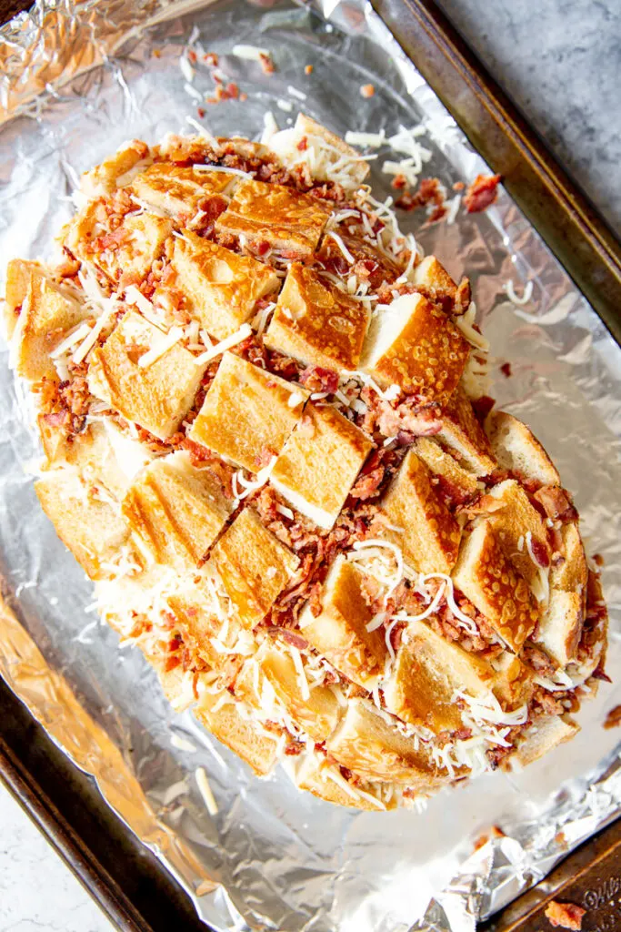 diced bacon and shredded cheese between square cuts into a sourdough loaf