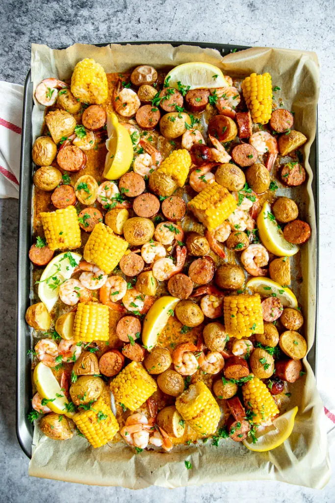 baked sheet pan shrimp boil with lemon slices and chopped parsley