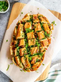 a loaf of pull apart garlic bread on parchment paper on a cutting board