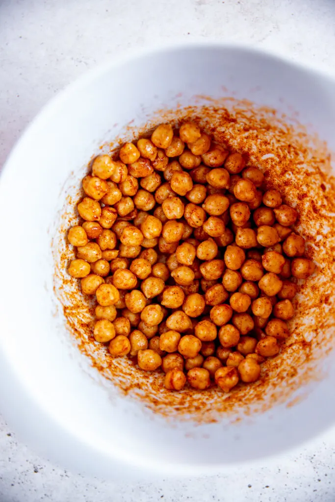 a white bowl filled with chickpeas covered in spices and oil