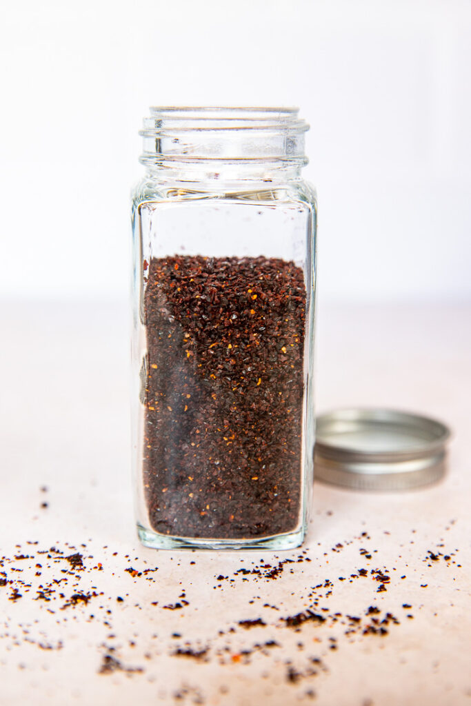 A glass spice jar filled with ancho chile powder.