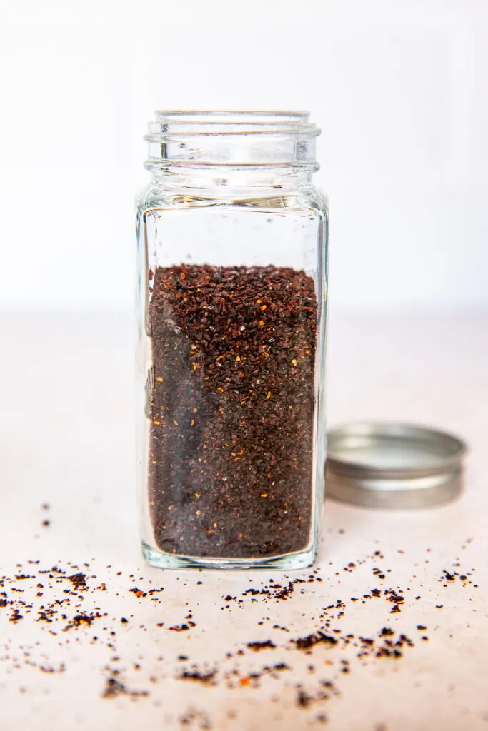 A glass spice jar filled with ancho chile powder.