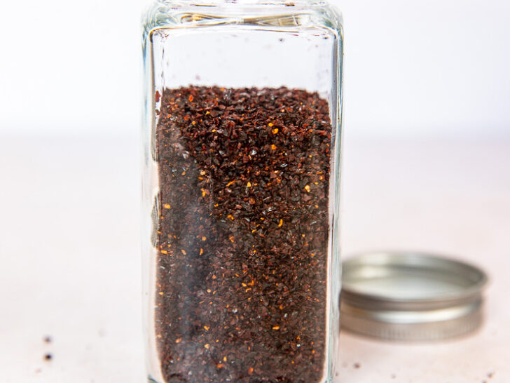 A glass spice jar filled with ancho chile powder.