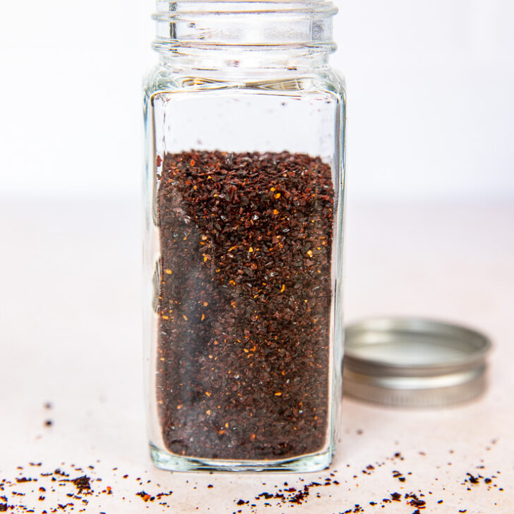 A glass spice jar filled with ancho chile powder.