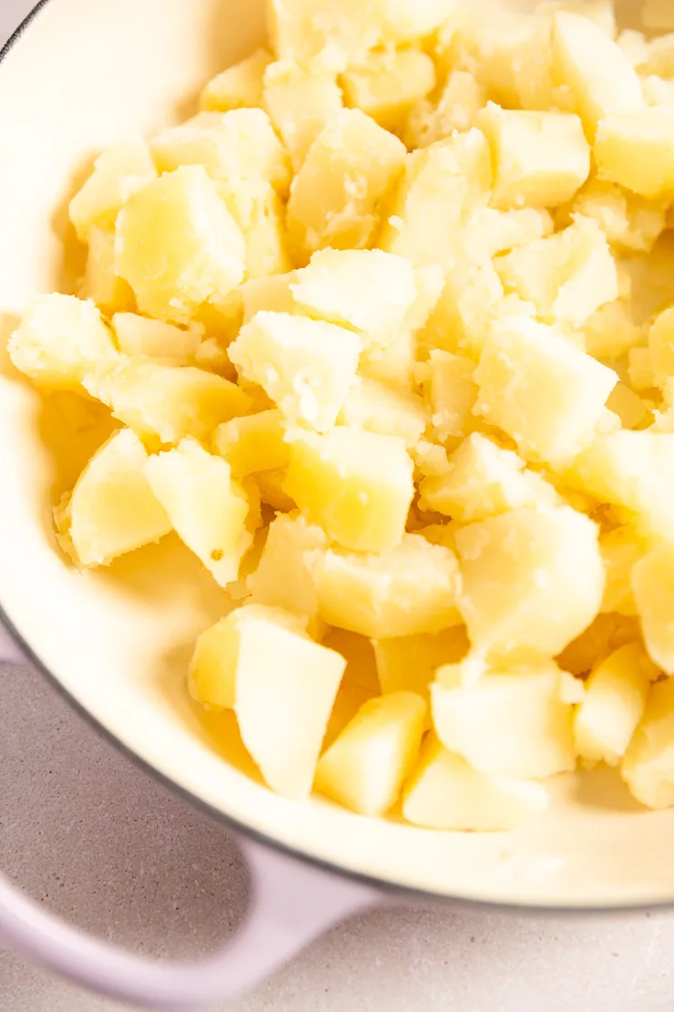 A lavender enameled cast iron pan filled with diced cooked potatoes.