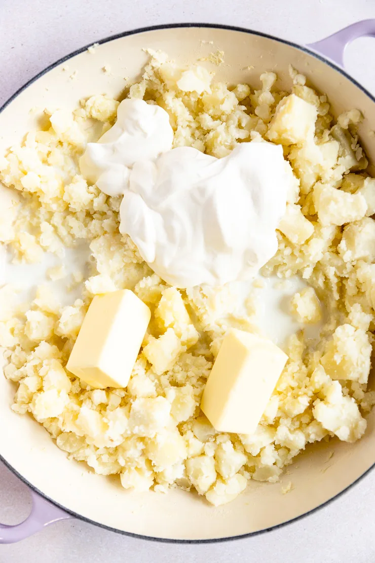 A lavender enameled cast iron pan filled with hand mashed potatoes,