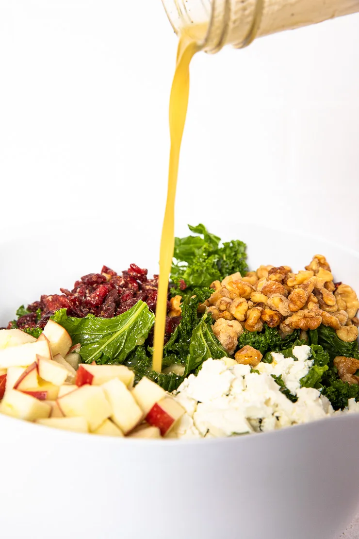 A shot of the honey lemon vinaigrette being poured into the salad bowl.