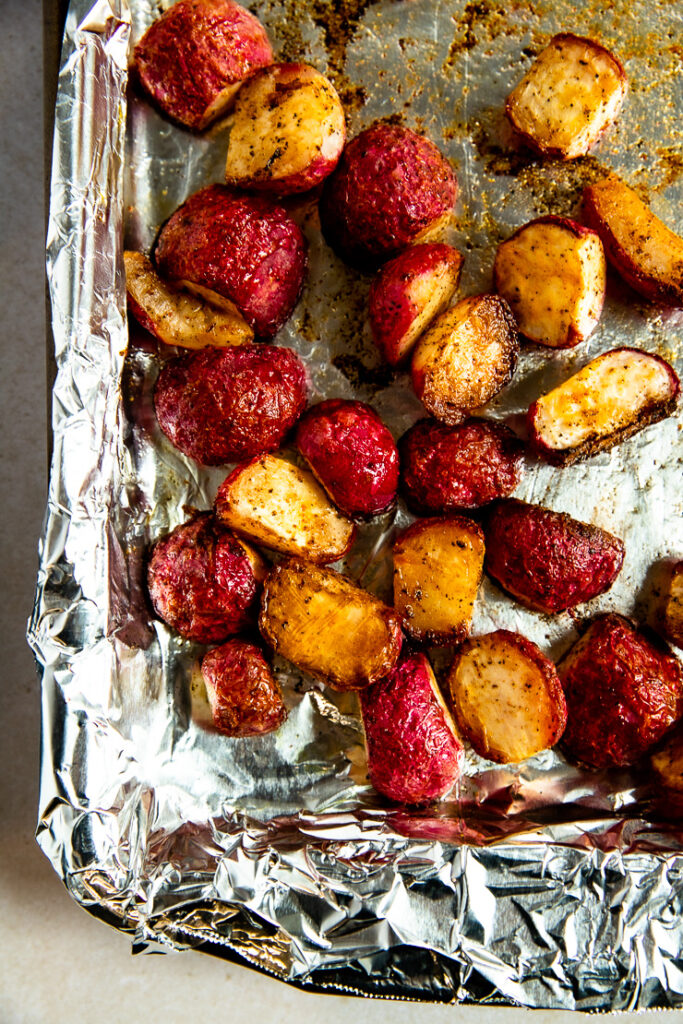 A prepared baking sheet with aluminum foil and roasted radishes.