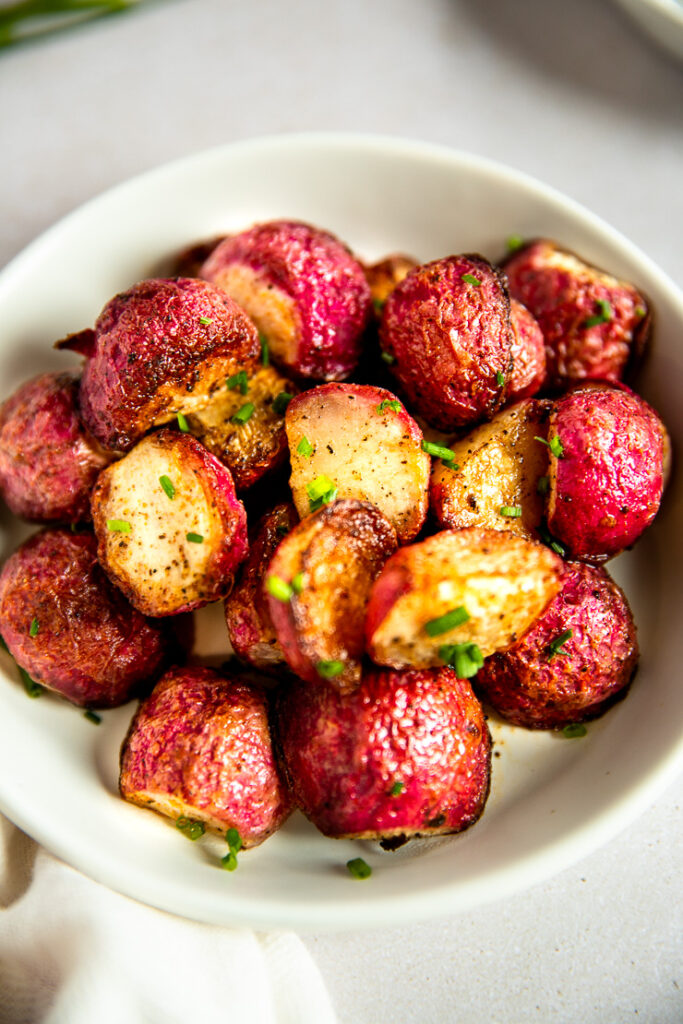 A close up of the crispy, roasted halves of roasted radishes with chives.