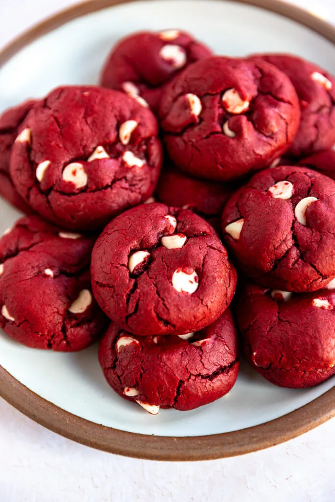 A close up of a few red velvet cake mix cookies with white chocolate chips poking out of the dough.
