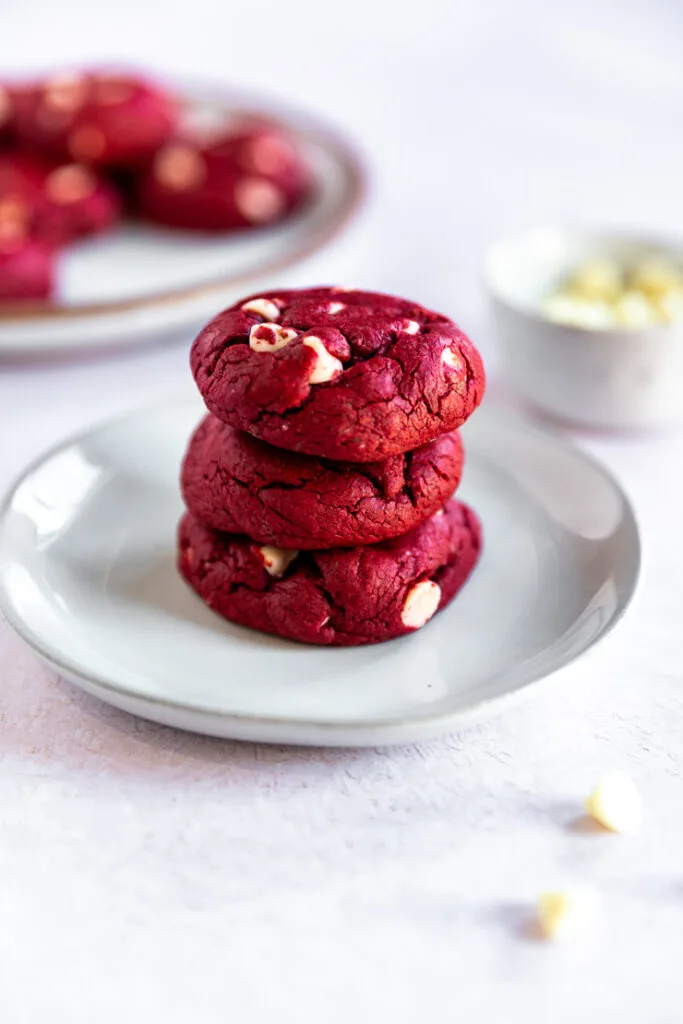 Three Red Velvet Cake Mix Cookies piled on top of each other on a small white plate.