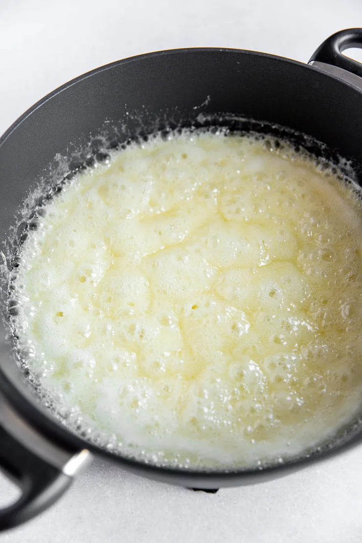 A large dark grey pot that's filled with bubbling melted corn syrup, butter, and sugar.