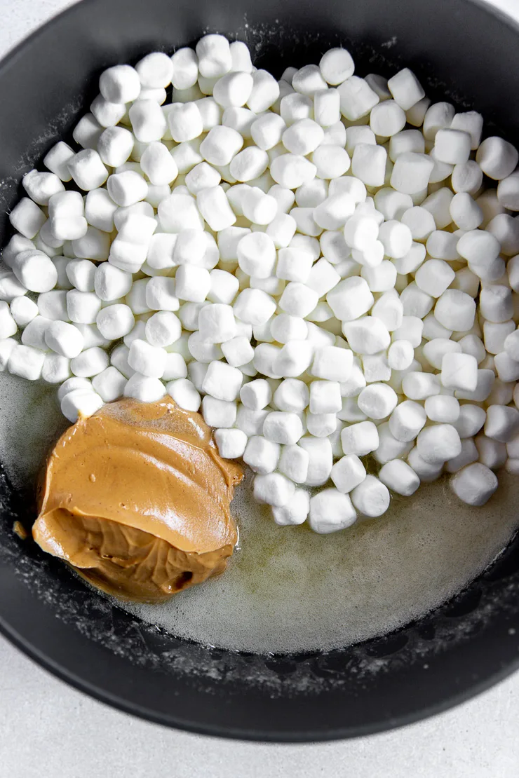 A dark grey pot filled with melted butter, mini marshmallows, and peanut butter.