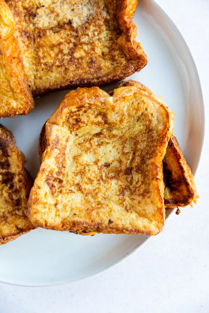 An overhead close up of brioche french toast stacked on top of each other.