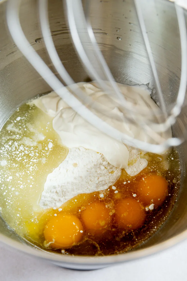 A mixing bowl filled with cake mix, sour cream, oil, and eggs.