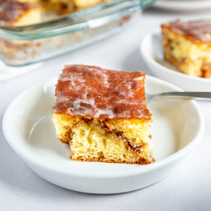 A front on shot of a slice of honey bun cake with a cinnamon swirl running through the middle.