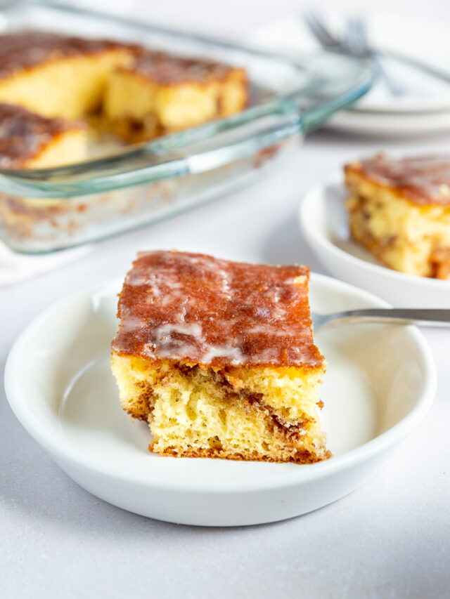 A front on shot of a slice of honey bun cake with a cinnamon swirl running through the middle.