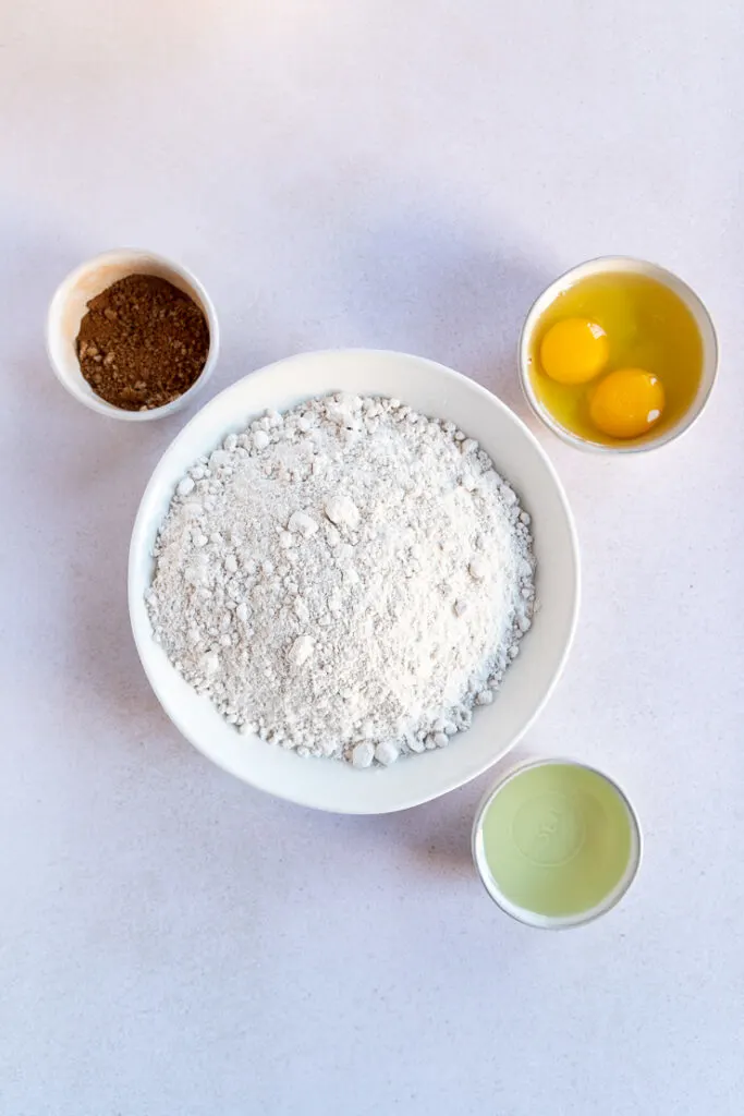 A bowl of cake mix, a bowl of eggs, a bowl of oil, and a bowl of cinnamon sugar mixture.