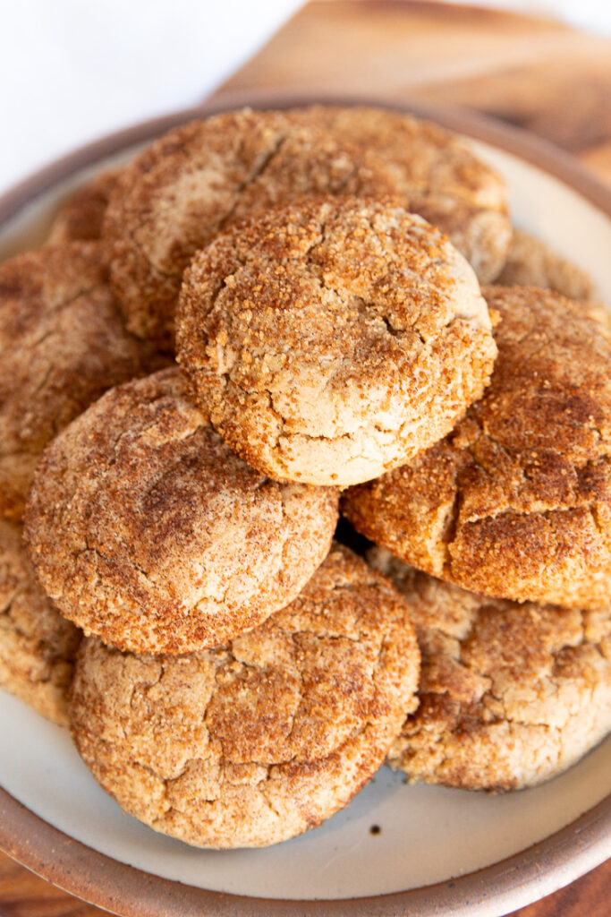 A close up of a plate of stacked spice cake mix cookies covered in brown sugar cinnamon.