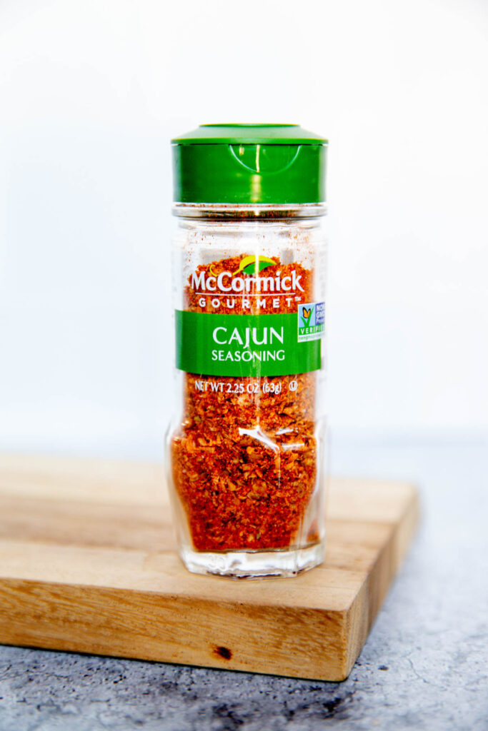 A jar of McCormick Gourmet Cajun Seasoning sits on a wooden surface with a light background, sparking curiosity about the Old Bay vs Cajun Seasoning debate among spice enthusiasts.
